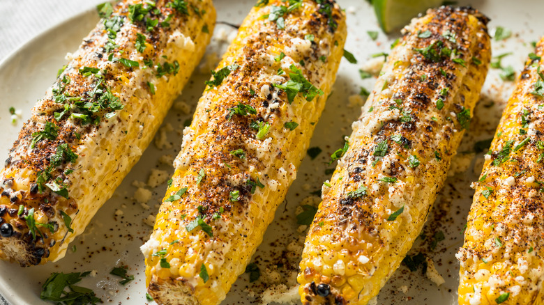 épis de maïs grillés avec du fromage émietté et de la poudre de chili