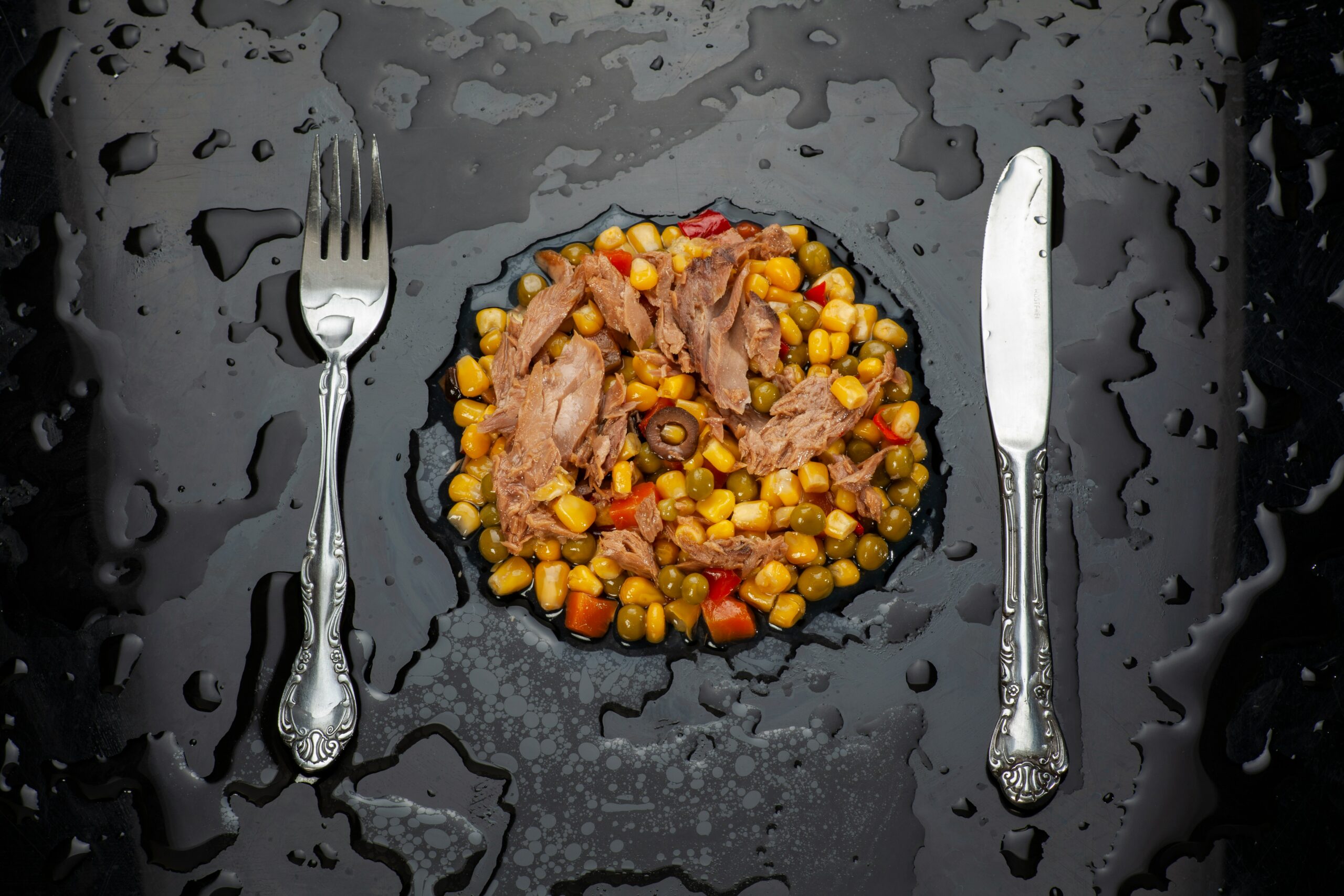 stainless steel fork and bread knife on black ceramic plate