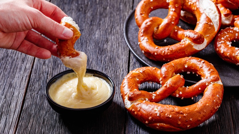 Tremper un bretzel dans une trempette au fromage