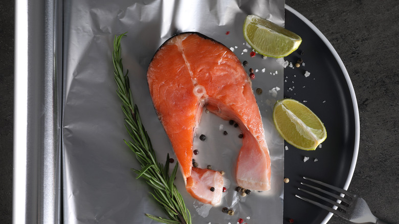 Poisson cru sur du papier aluminium à côté de quartiers de citron vert 