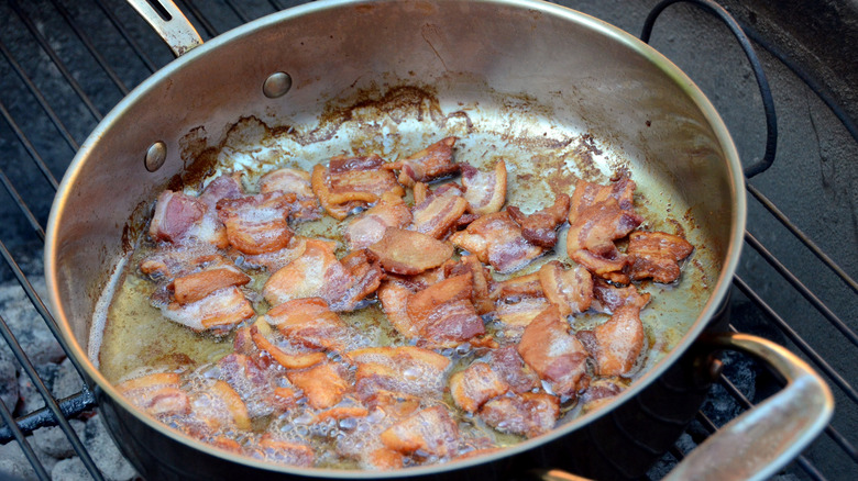 morceaux de bacon frits dans la graisse dans une poêle en métal