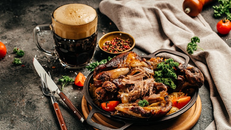 Un verre de bière à côté d'un plat de viande tendre et effilochée