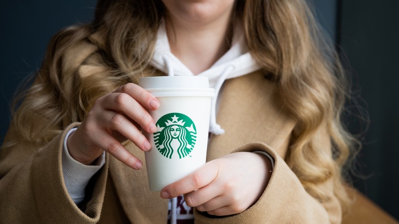 Personne tenant une tasse Starbucks