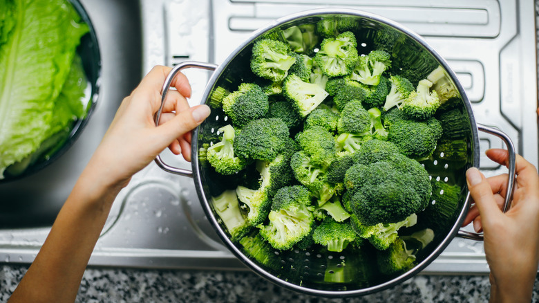 mains tenant une passoire de brocoli