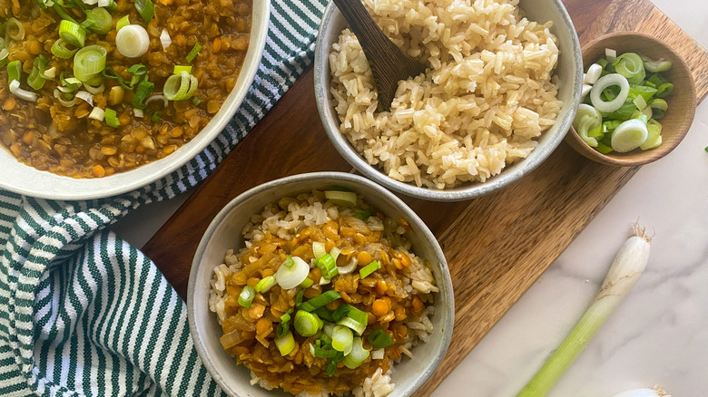 Bols de lentilles à côté de riz et d'oignons verts 