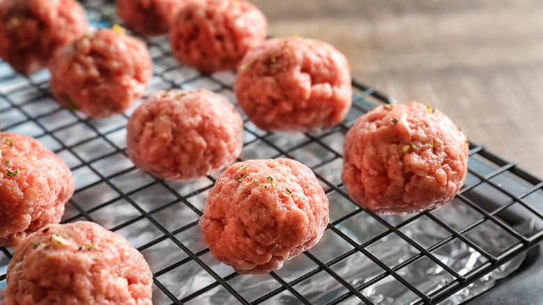 Boulettes de viande crues sur une grille de cuisson