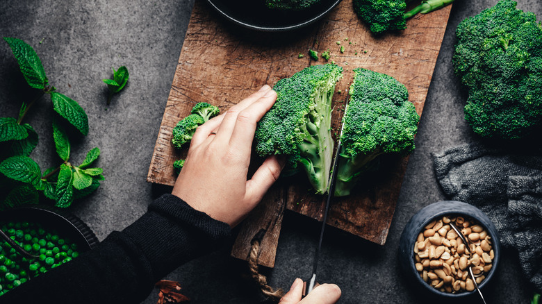 les mains d'une personne coupant une couronne de brocoli