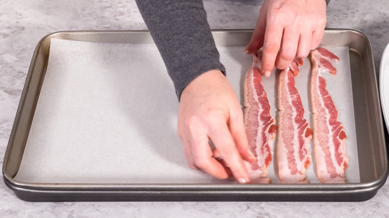 Placer des tranches de bacon crues sur une plaque à pâtisserie