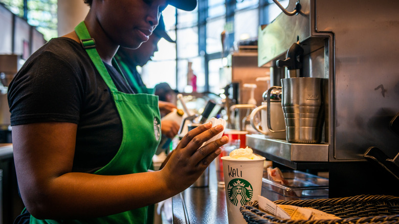 Un barista de Starbucks prépare une boisson chaude avec de la crème fouettée