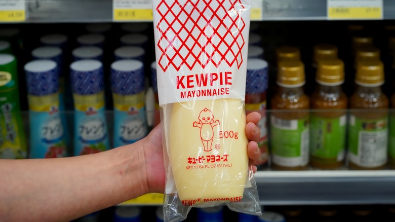 Personne tenant de la mayonnaise Kewpie dans une épicerie