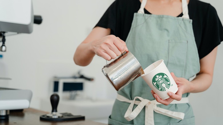 Barista versant du lait dans une tasse