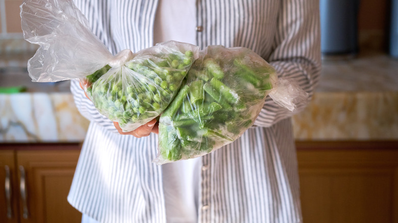 personne tenant des haricots verts congelés