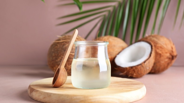 huile de coco dans un pot à côté de noix de coco fraîche