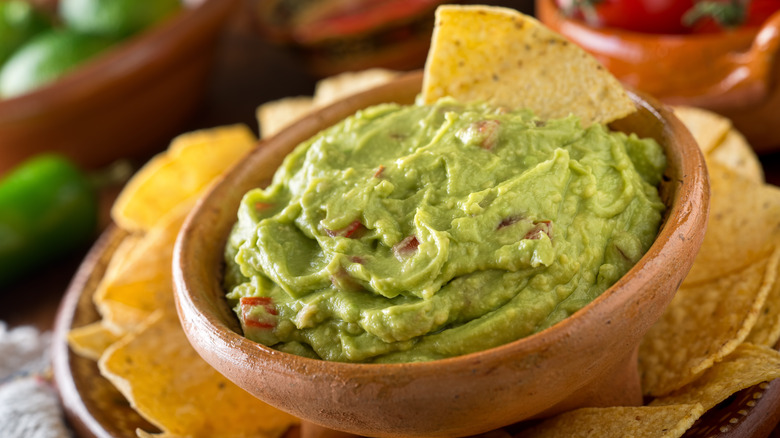 Guacamole crémeux dans un bol en bois avec chips de tortilla