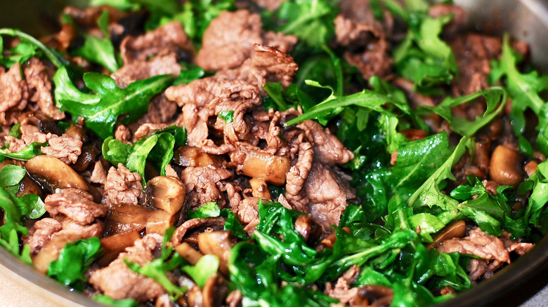 Gros plan sur du bœuf cuit et des légumes verts dans une poêle