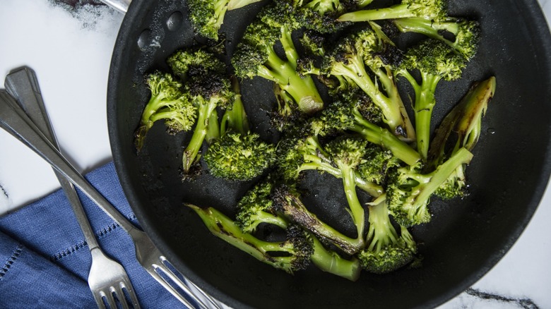 Brocoli carbonisé dans une poêle à côté de fourchettes