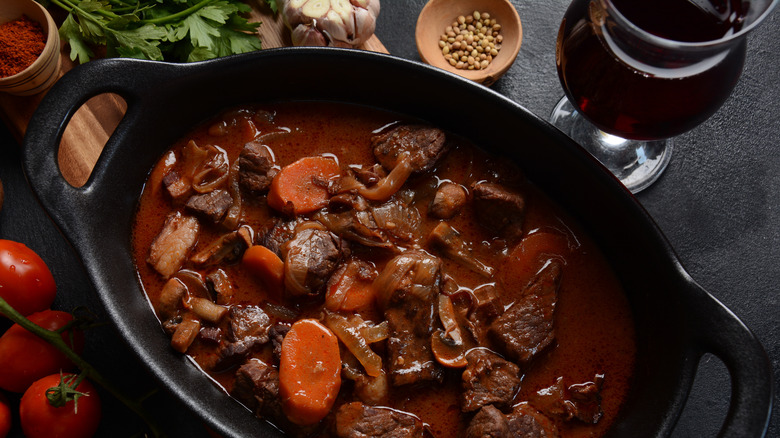 Ragoût de boeuf en cocotte avec un verre de vin rouge