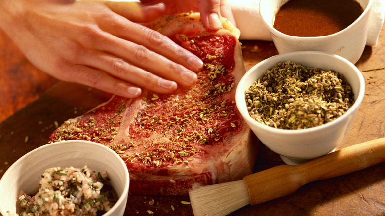 Cuisinier amateur frottant l'assaisonnement sur un steak