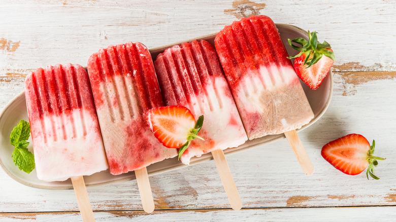 sucettes glacées à la fraise et à la crème sur une table en bois