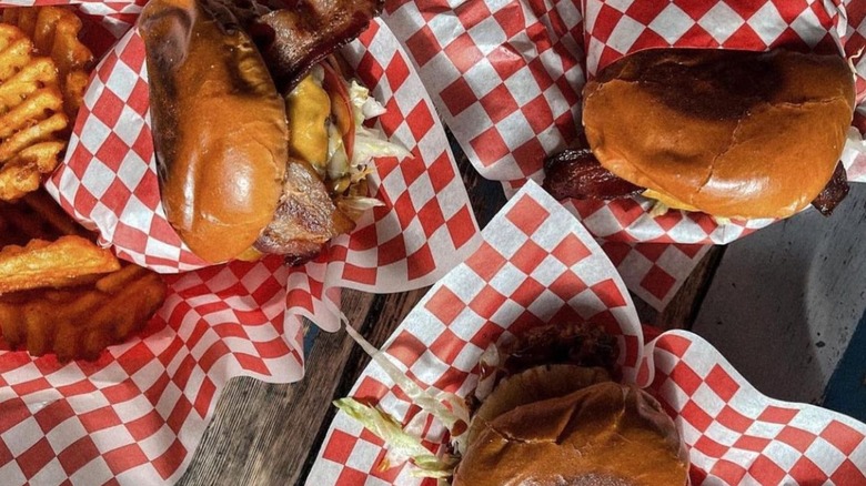 trois hamburgers dans du papier à carreaux rouges et blancs