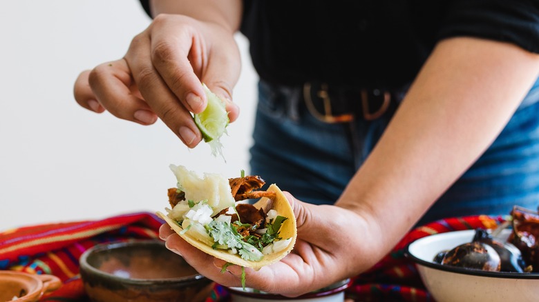 Mains pressant du citron vert sur un taco