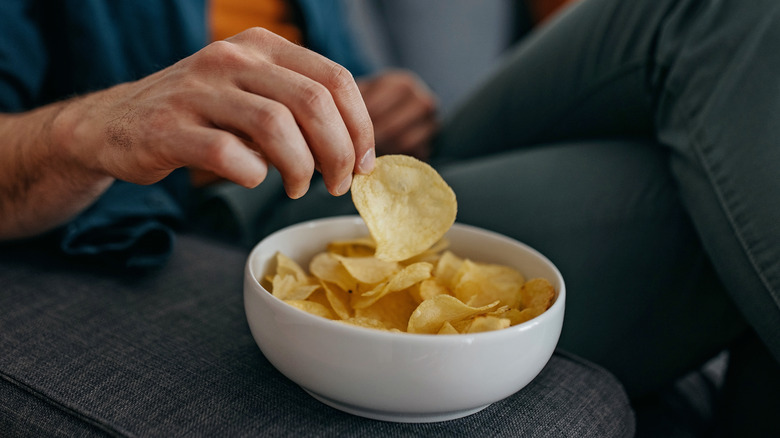 Une main attrape une chips de pomme de terre