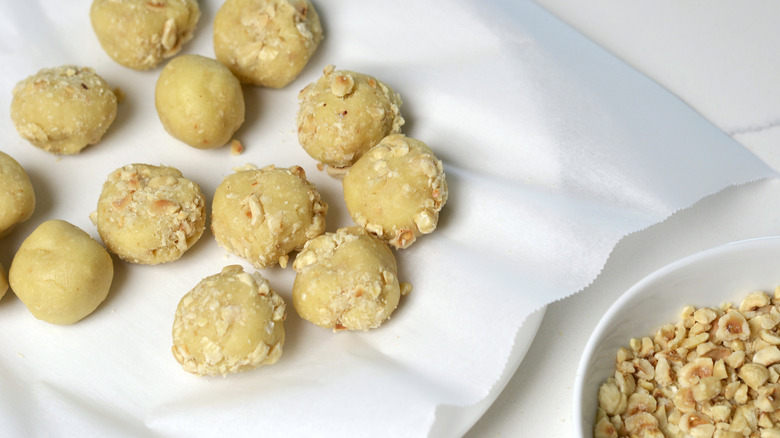 Pâte à biscuits empreinte de pouce aux noisettes roulée dans des noisettes concassées