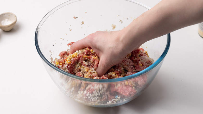 mélanger à la main les ingrédients des boulettes de viande 