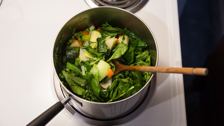 légumes verts à feuilles en train de cuire dans une casserole 