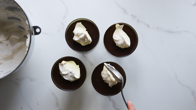 cuillère ajoutant de la crème fouettée sur le pudding