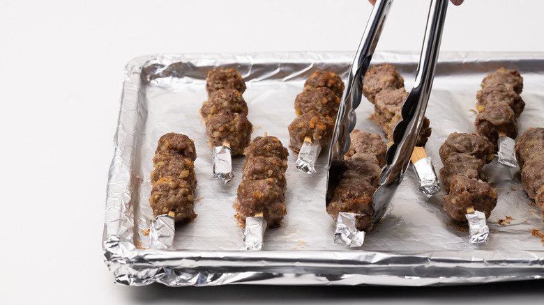 retourner des boulettes de viande cuites sur des brochettes