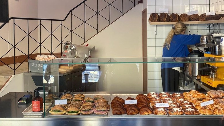 femme travaillant derrière une vitrine à pâtisserie avec des sandwichs