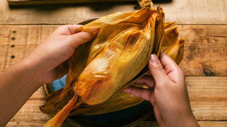 main ouvrant un tamale 