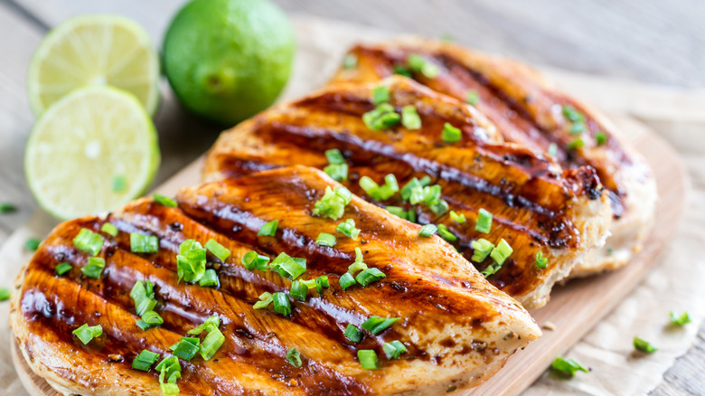 Poitrines de poulet grillées avec des citrons verts en arrière-plan 