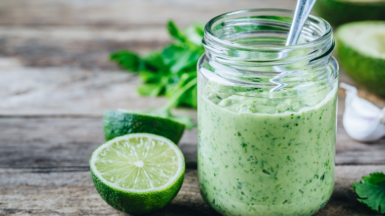 Pot de vinaigrette verte à côté du citron vert coupé 