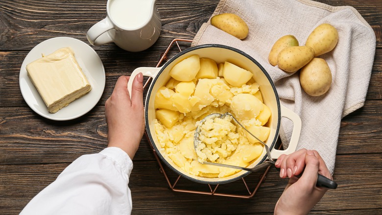 Personne écrasant des pommes de terre dans une poêle