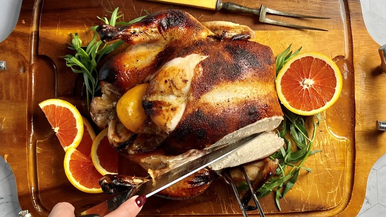 découper un poulet entier rôti sur une planche de bois