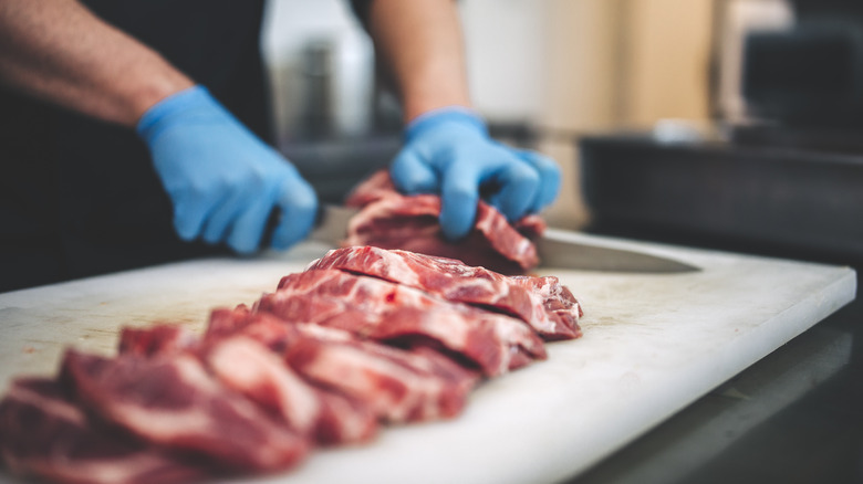 boucher découpant de la viande crue