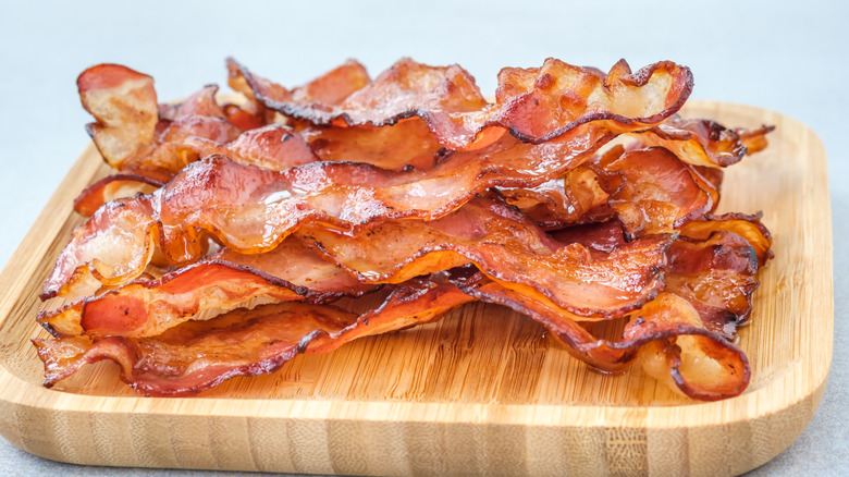 Un tas de bacon croustillant est posé sur une planche de bois 