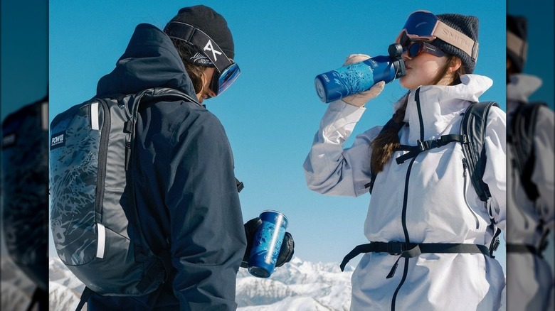 Snowboarders tenant des bouteilles d'eau