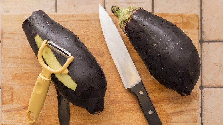 aubergine légèrement pelée avec éplucheur et couteau